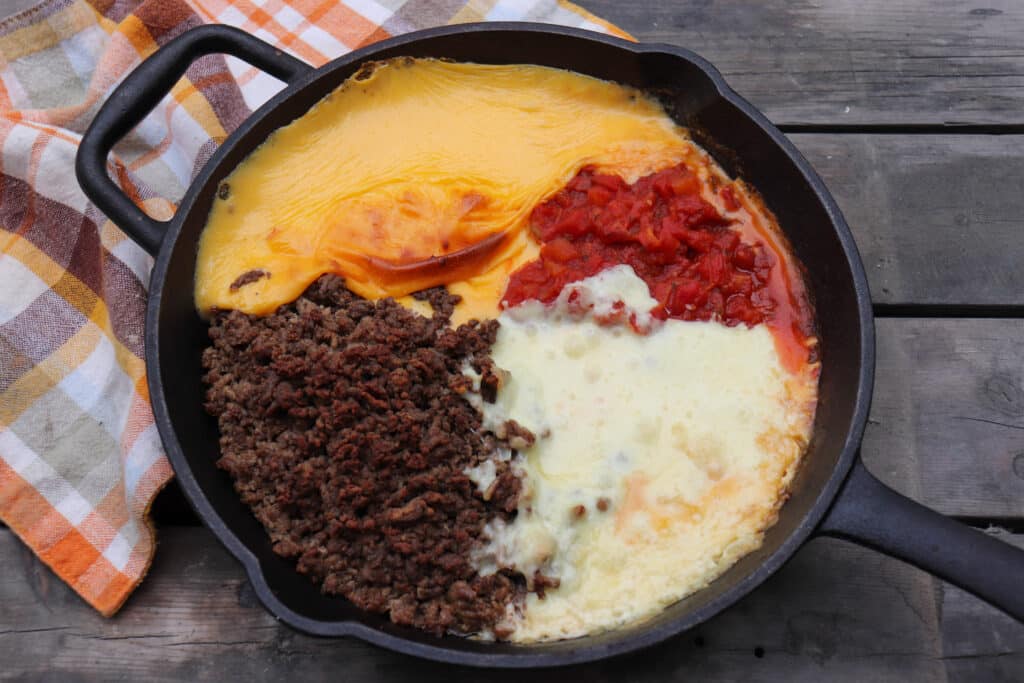 Rotel dip ingredients melted together in a cast iron skillet.