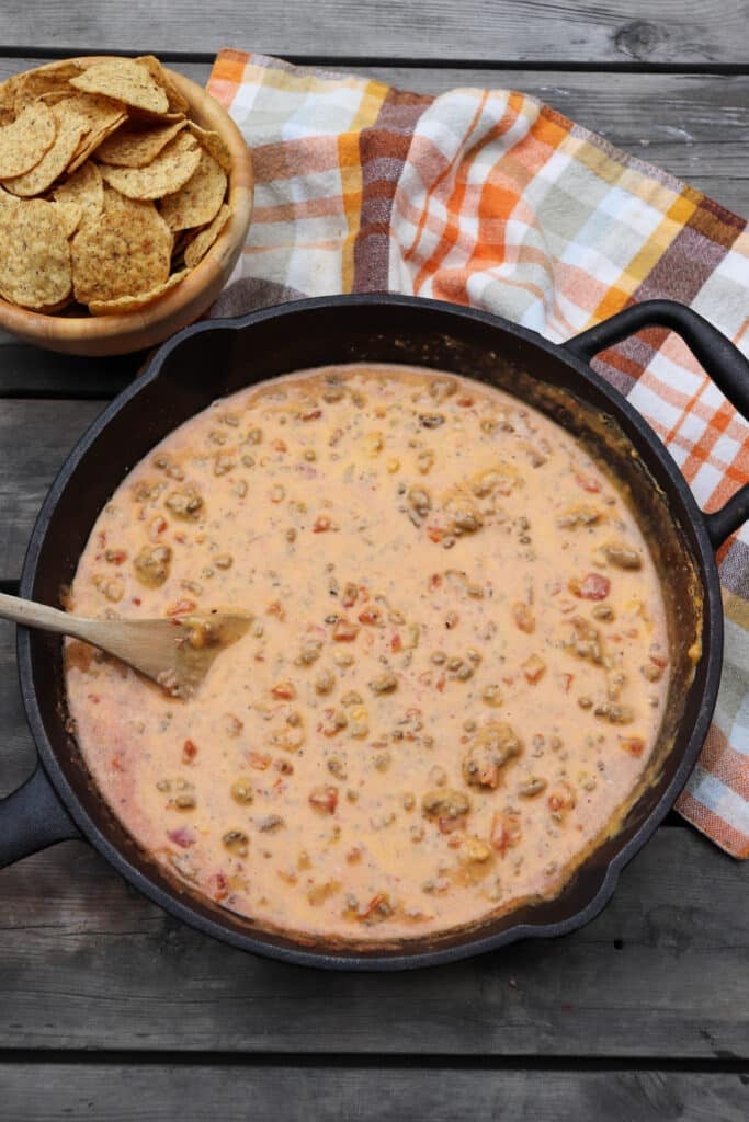 Cheese dip with ground beef and diced tomatoes in a skillet.
