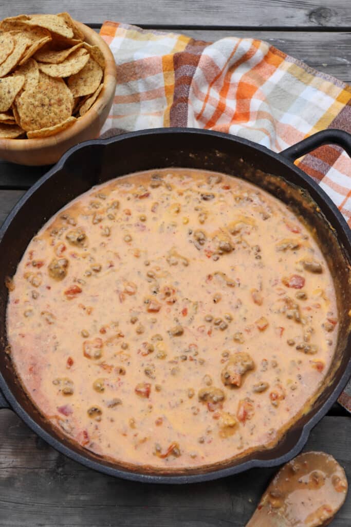 Cheese dip with ground beef, sausage and diced tomatoes in a skillet.