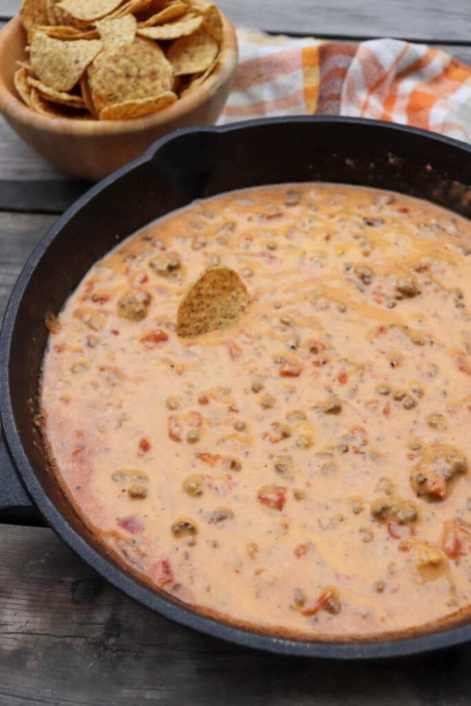 Cheese dip with ground beef and diced tomatoes in a cast iron skillet.