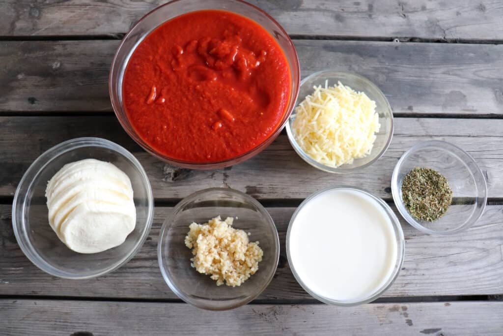 Tomato mozzarella chicken ingredients in clear glass bowls.
