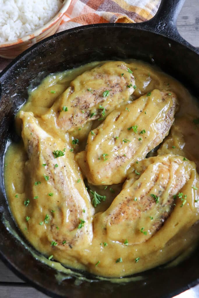 Cooked chicken breasts in a honey mustard sauce in a cast iron skillet.