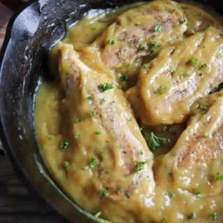 Cooked chicken breasts in a honey mustard sauce in a cast iron skillet.