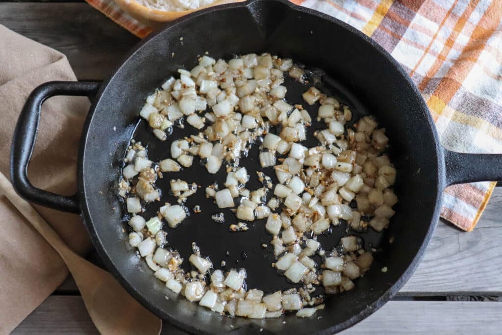 Diced onion and garlic sauteed in a cast iron pan.
