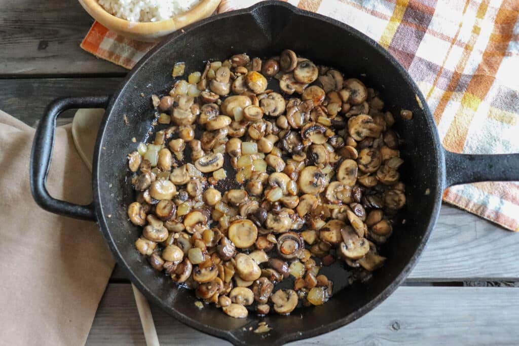Button mushrooms, sliced and cooked in a cast iron skillet.
