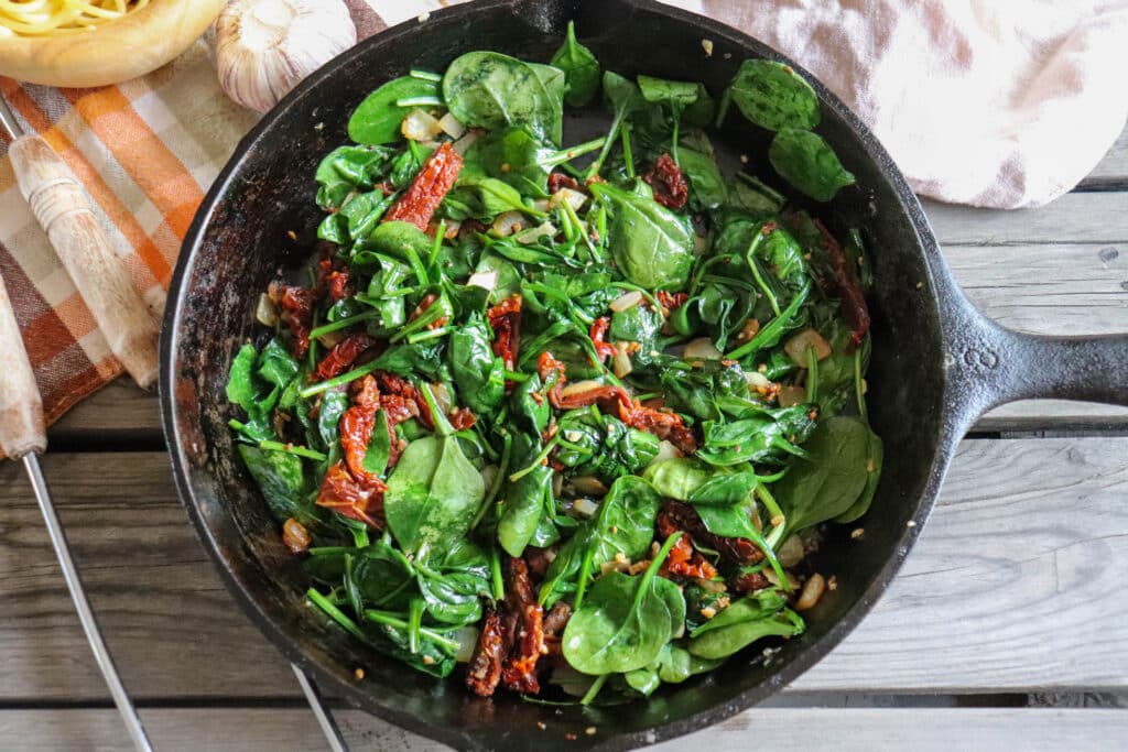 Spinach and sun dried tomatoes in a cast iron skillet.