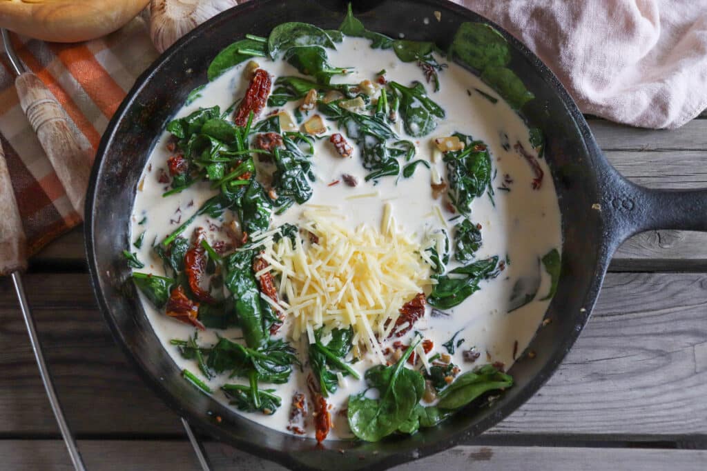 Spinach, sun dried tomatoes and cream in a cast iron skillet.