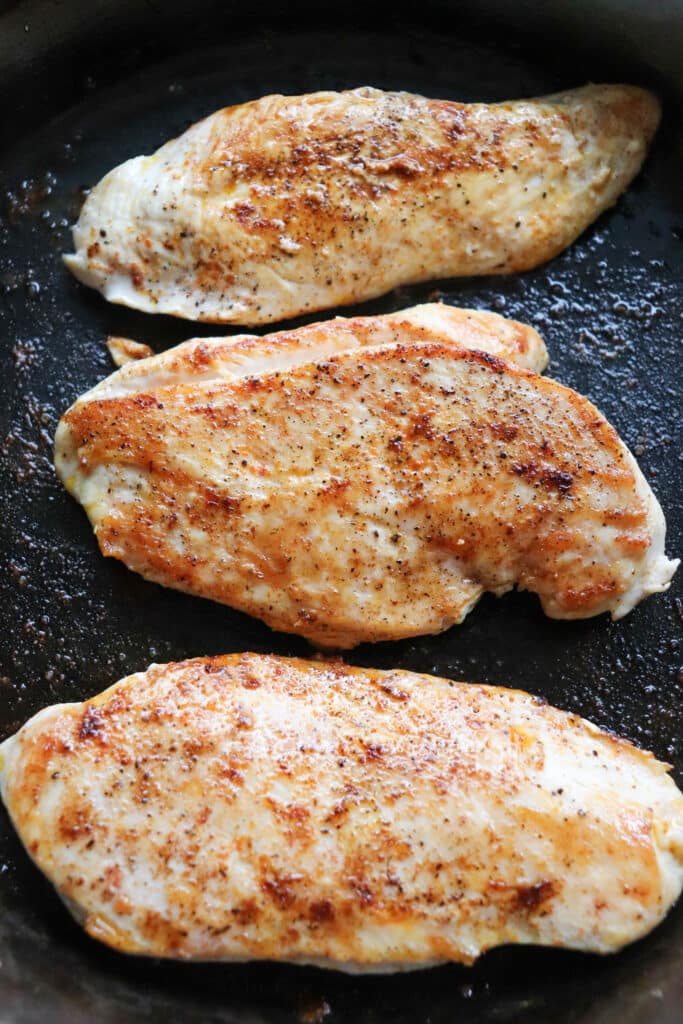 Cooked chicken breasts on a cast iron skillet.