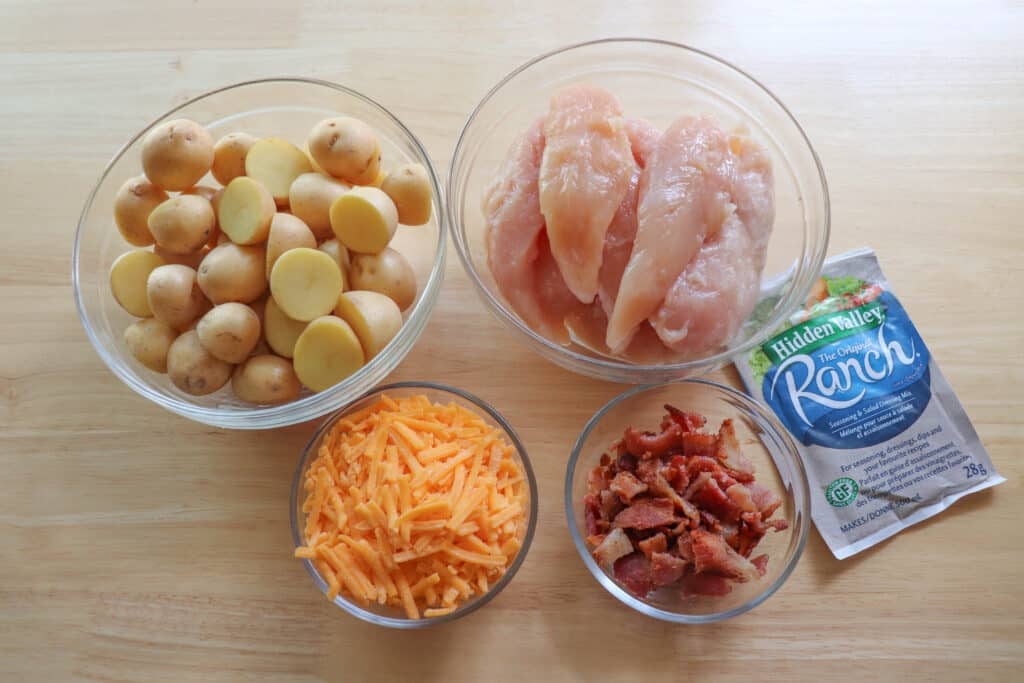 Chicken Bacon Ranch ingredients in clear glass bowls on a wooden table.