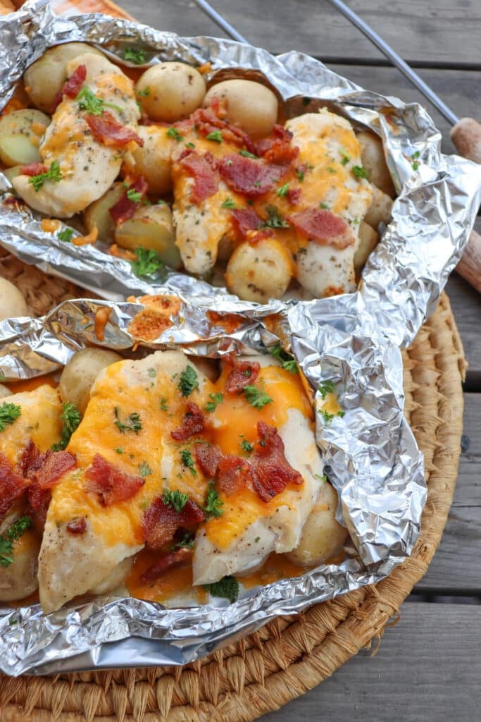 Chicken bacon ranch with melty cheese in foil packets on a picnic table.