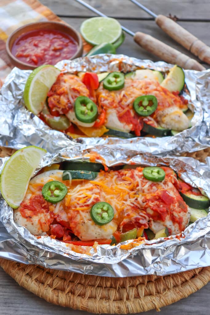 Salsa chicken foil packs on a wooden picnic table.