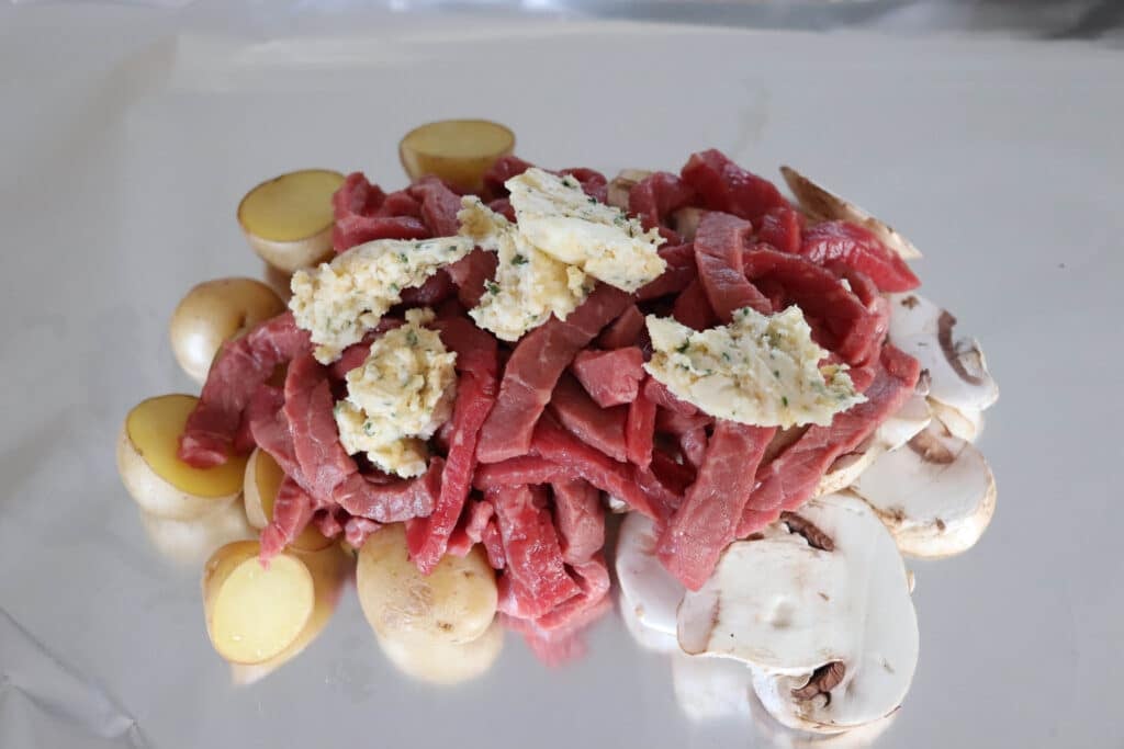 Steak and mushroom ingredients on foil.