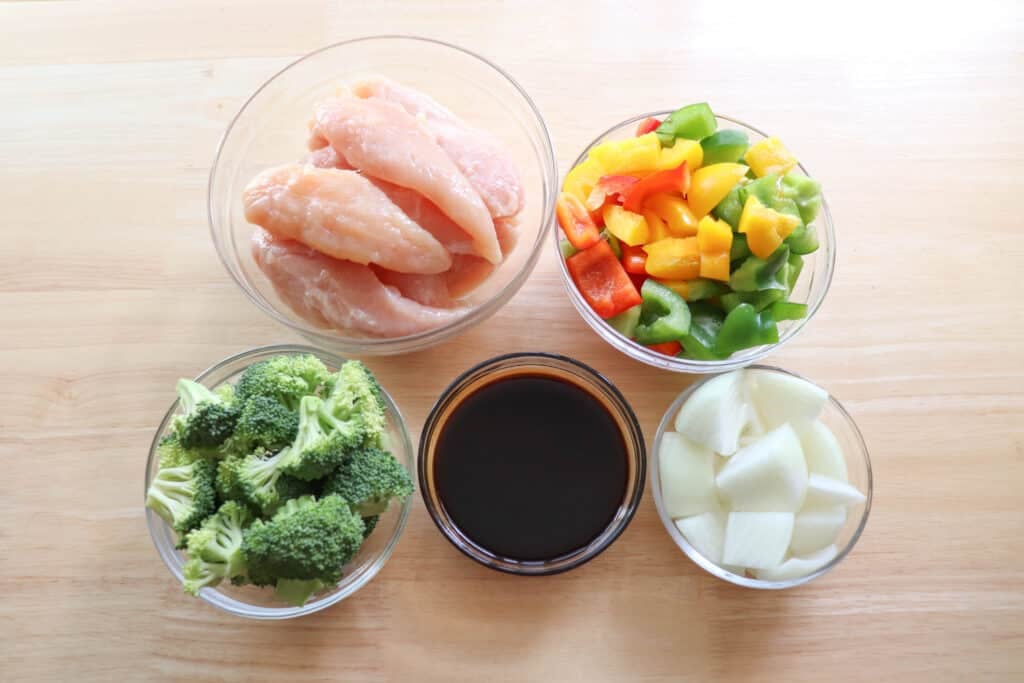 Teriyaki chicken foil packet ingredients in bowls on a wooden table.