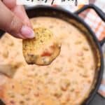 A hand holding a chip dipped in a creamy, beefy cheese sauce over a skillet filled with more of the dip. A checkered cloth is partially visible in the background. The text reads Skillet Dip Cheesy Beef and campfirefoodie.com.