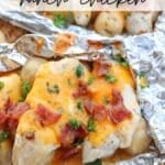 Foil packets filled with ranch-seasoned chicken breast topped with melted cheese, crispy bacon bits, and garnished with parsley. Small potatoes accompany the chicken, all enclosed in aluminum foil. Text reads Foil Packet Ranch Chicken.