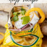Open bag of onion-flavored rings topped with chili, sour cream, shredded cheese, and chopped green onions. A whole onion ring is placed on the edge of the bag. Text reads WALKING CHILI dogs recipe and campfirefoodie.com.