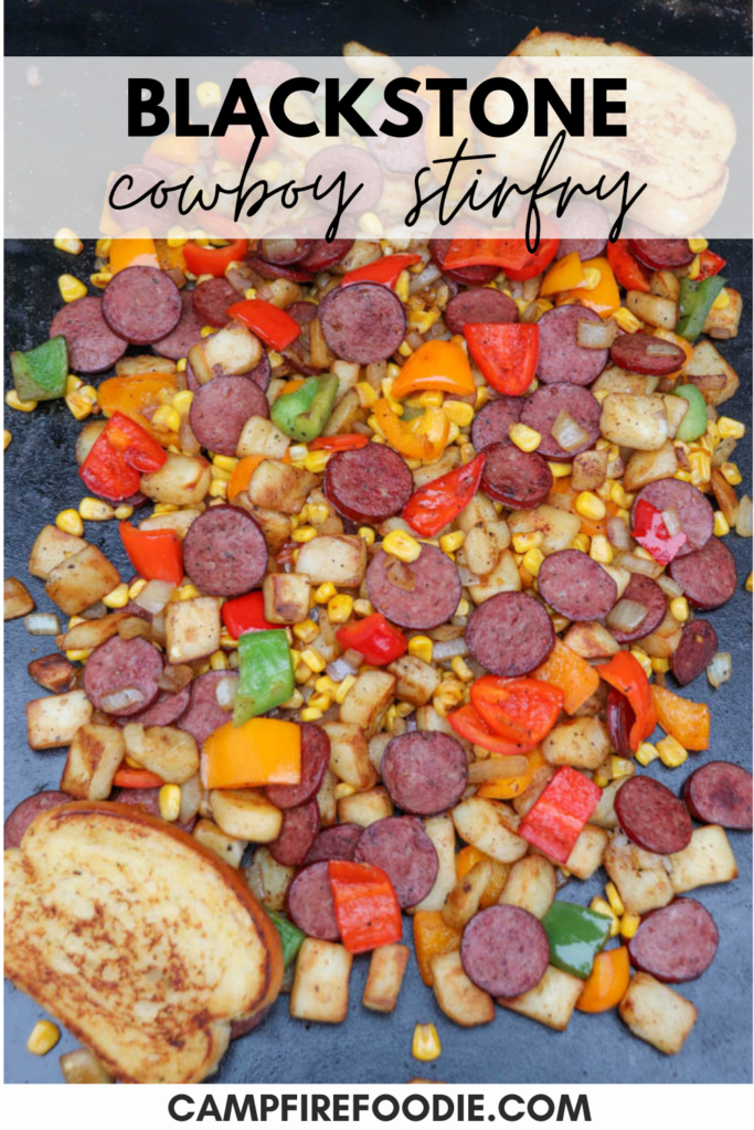 A colorful stir-fry with sliced sausage, diced potatoes, corn, red and green bell peppers, and onions, cooked on a griddle with two slices of toasted bread. Text reads Blackstone cowboy stir-fry campfirefoodie.com.