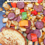 A skillet with sliced sausage, diced potatoes, bell peppers, onions, and corn, served with a piece of toasted bread. Text reads Blackstone Cowboy Stirfry and campfirefoodie.com at the bottom.