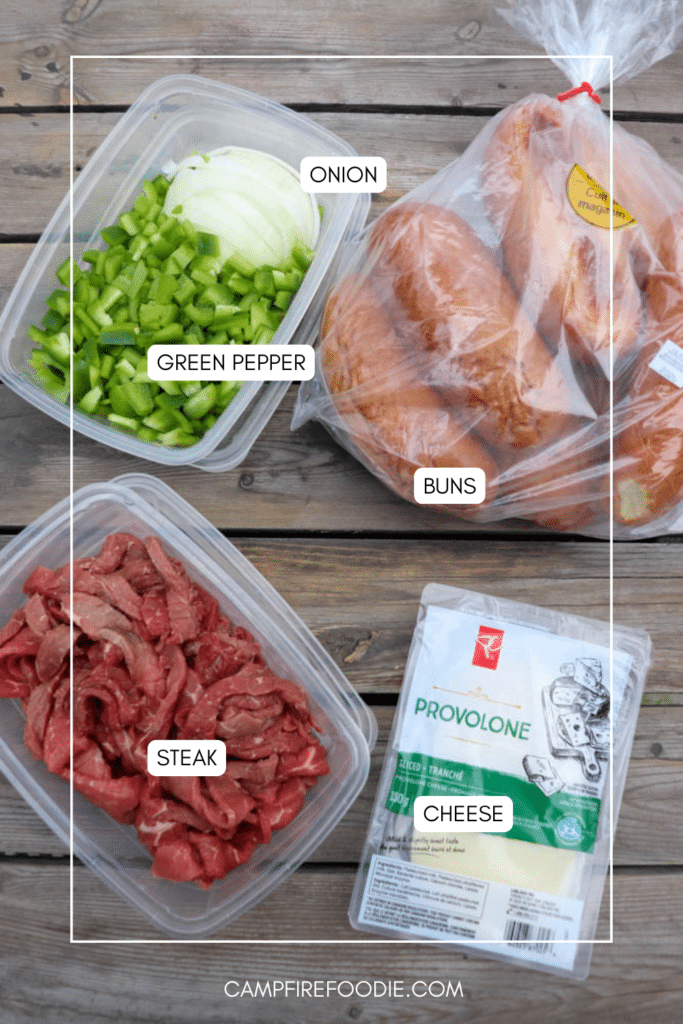 Plastic containers with sliced onion and green pepper, a pack of soft buns, raw sliced steak, and a package of provolone cheese arranged on a wooden surface. Each item is labeled.