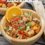 Two wooden bowls filled with Blackstone breakfast hash, featuring potatoes, eggs, bacon, peppers, and green onions, garnished with an orange slice. The text reads Blackstone breakfast hash and campfirefoodie.com.