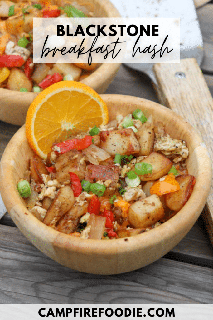 Two wooden bowls filled with Blackstone breakfast hash, featuring potatoes, eggs, bacon, peppers, and green onions, garnished with an orange slice. The text reads Blackstone breakfast hash and campfirefoodie.com.