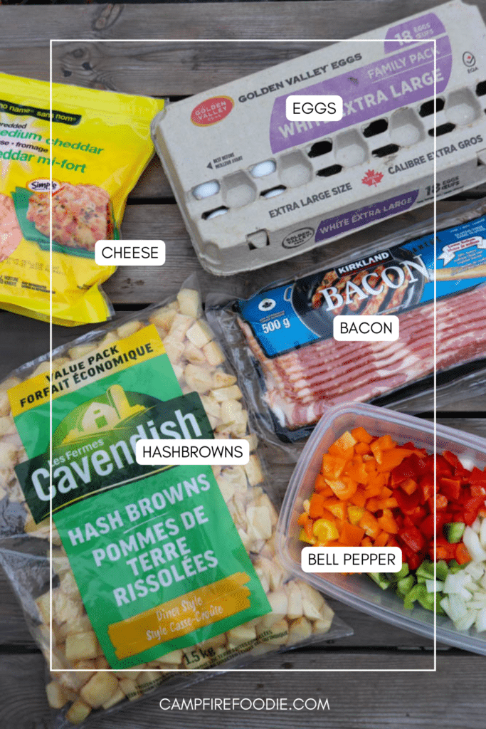 A photo displays packaged ingredients on a wooden surface: a carton of extra-large eggs, a bag of shredded cheese, sliced bacon, a bag of frozen hashbrowns, and a container of chopped bell peppers.