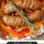 Two cooked sausages atop sliced red and yellow bell peppers with onions, garnished with a sprig of rosemary, all in a foil packet. Text reads: “Foil Packet Sausage & Peppers. campfirefoodie.com.”.