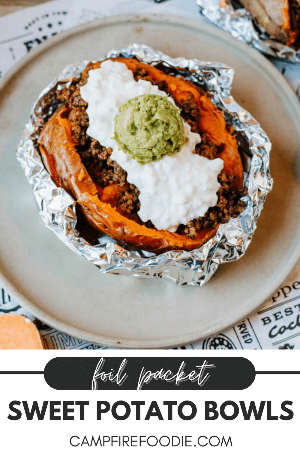 A baked sweet potato in foil, topped with seasoned ground meat, cottage cheese, and a dollop of guacamole, served on a plate. Text reads: Foil packet sweet potato bowls campfirefoodie.com.