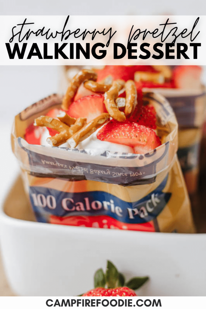 A 100-calorie snack bag is filled with whipped cream, sliced strawberries, and pretzel pieces, creating a strawberry pretzel walking dessert. The image is labeled “STRAWBERRY PRETZEL WALKING DESSERT.”.