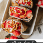 Three paper snack bags filled with layers of strawberries, pretzels, and cream are displayed on a tray, with text reading “walking dessert Strawberry Pretzel campfirefoodie.com” at the bottom.